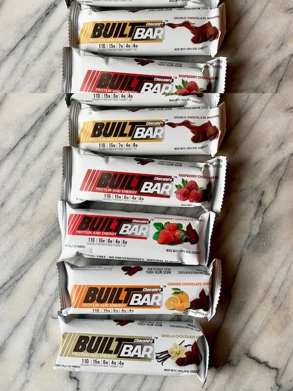 A line of Built Bars showcasing a variety of flavors lined up on a counter top.