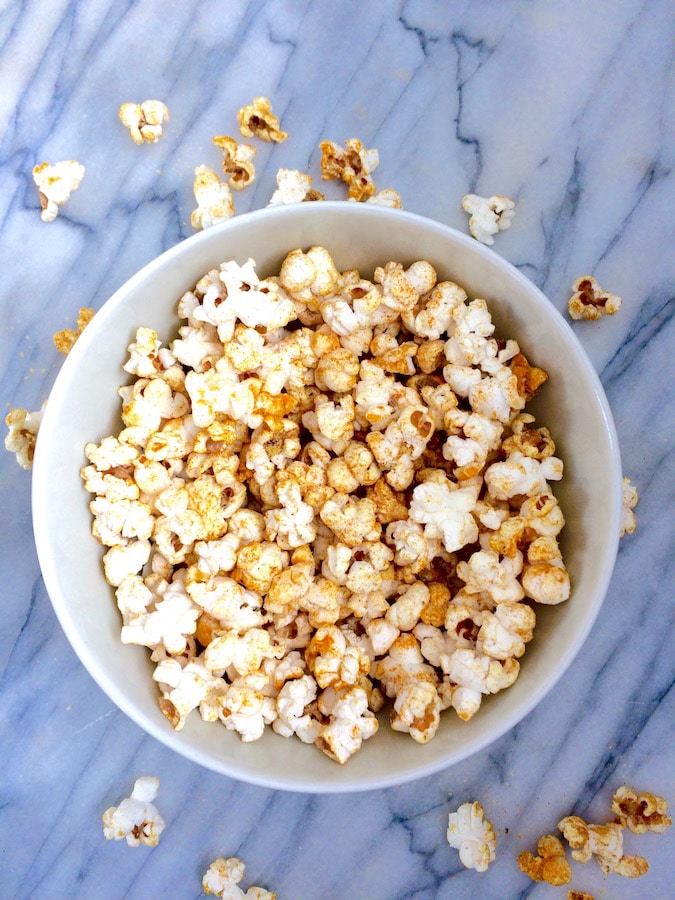 A bowl of healthy turmeric popcorn that's superfood-ified with colorful turmeric.